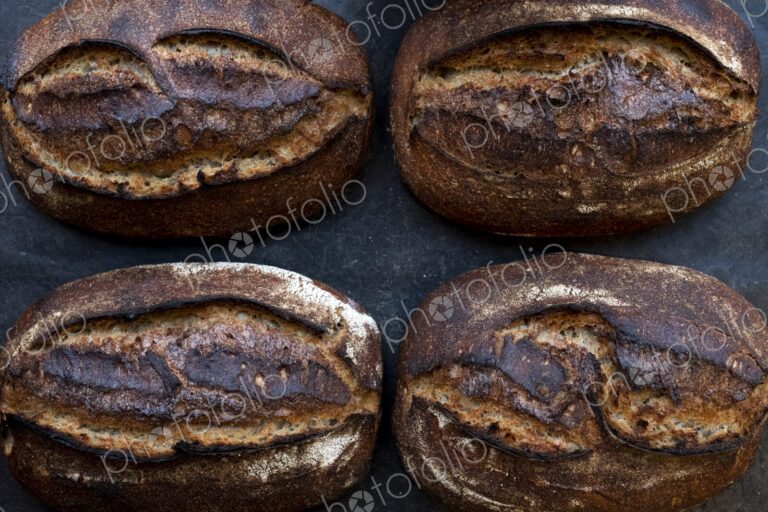 High angle close up of four freshly baked loaves of bread in an artisan bakery.