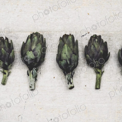 High angle close up of fresh artichokes on grey background. High angle close up of fresh artichokes on grey background.