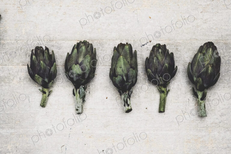 High angle close up of fresh artichokes on grey background.