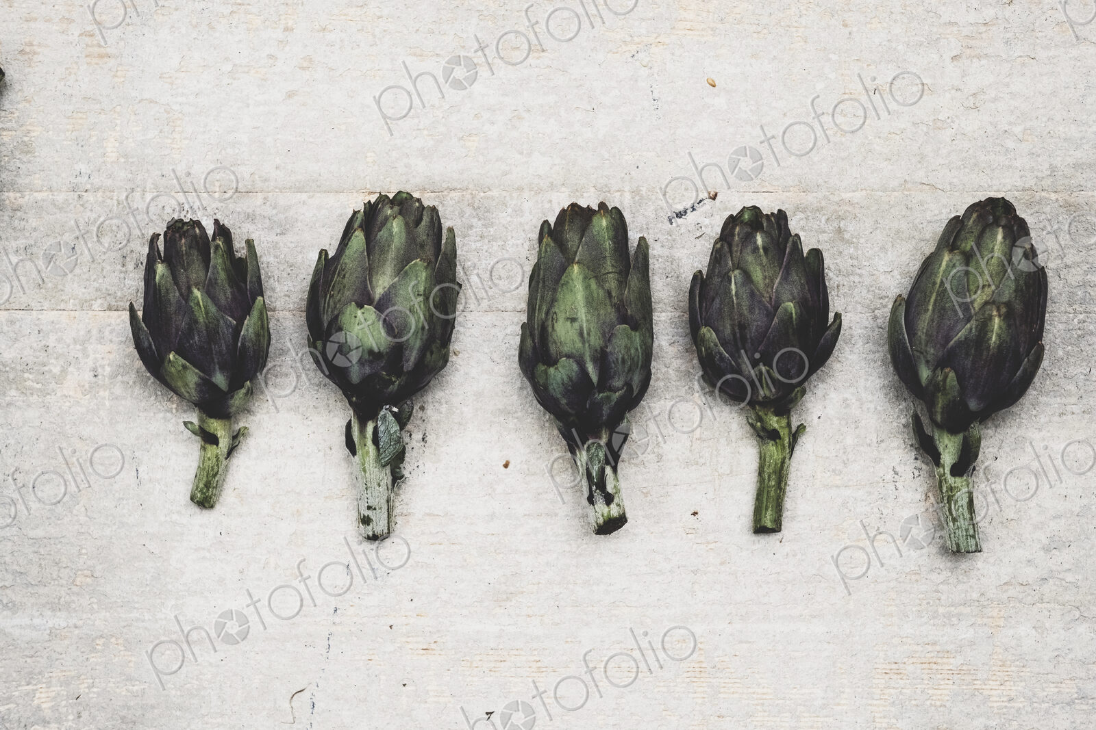 High angle close up of fresh artichokes on grey background.
