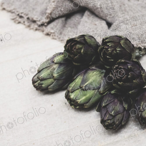 High angle close up of fresh artichokes on grey background. High angle close up of fresh artichokes on grey background.