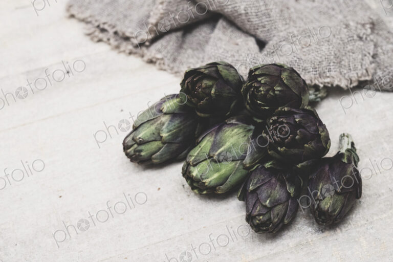 High angle close up of fresh artichokes on grey background.
