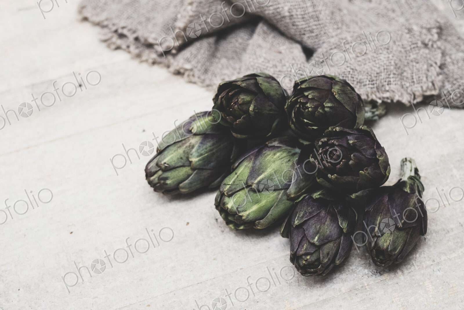 High angle close up of fresh artichokes on grey background.