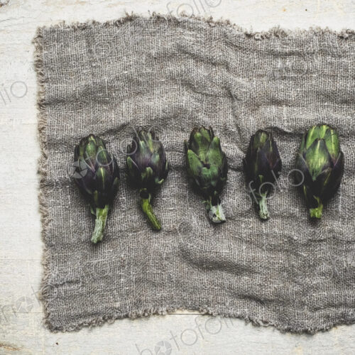 High angle close up of fresh artichokes on grey cloth.
