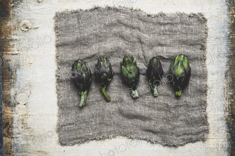 High angle close up of fresh artichokes on grey cloth.