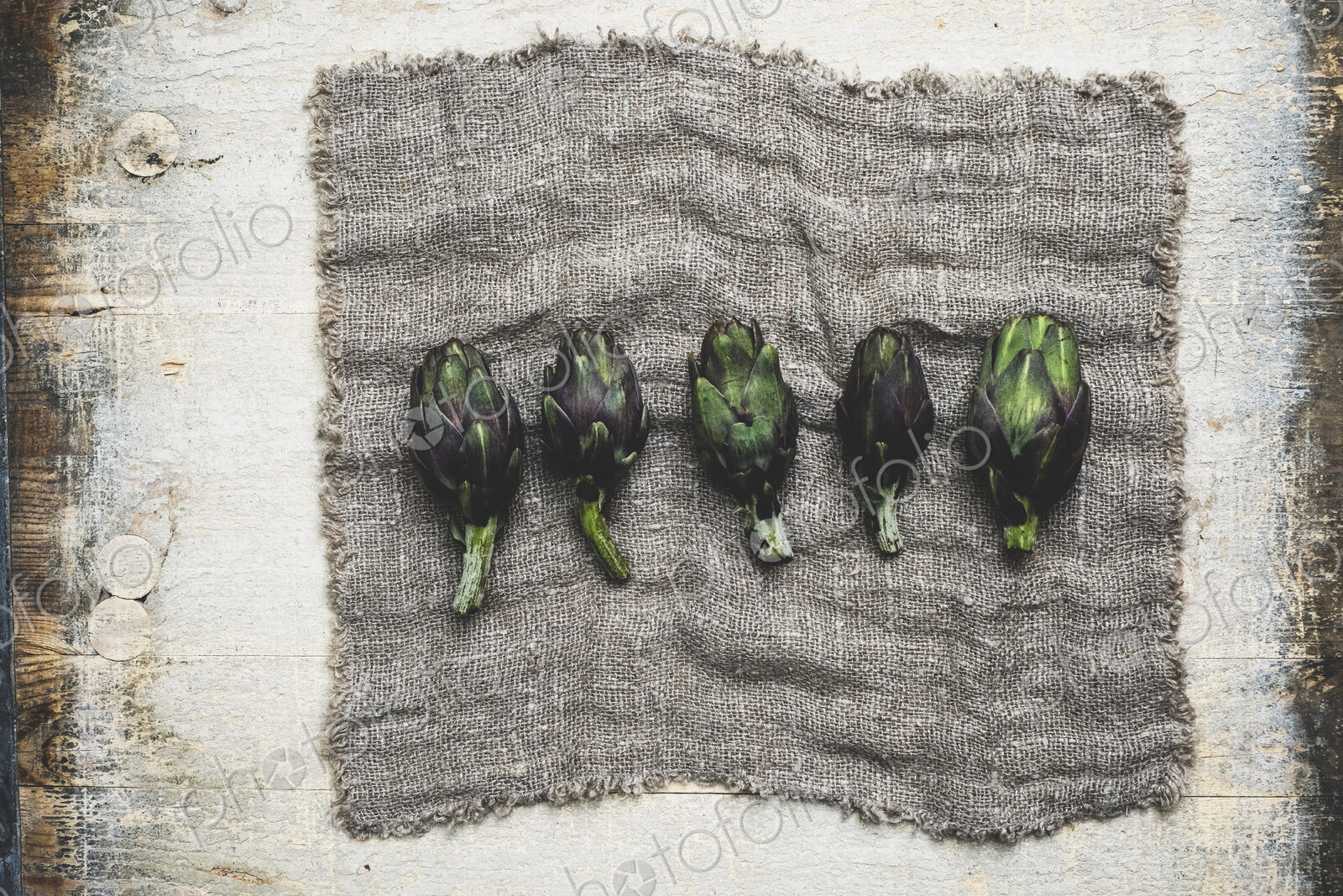 High angle close up of fresh artichokes on grey cloth.