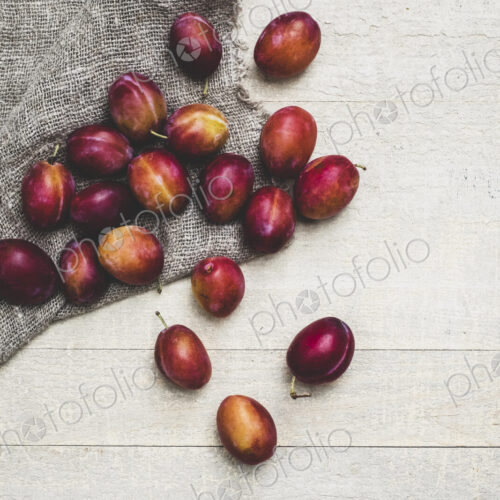 High angle close up of fresh damsons on grey cloth. High angle close up of fresh damsons on grey cloth.