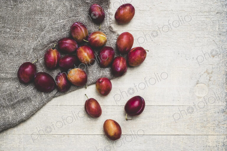 High angle close up of fresh damsons on grey cloth.