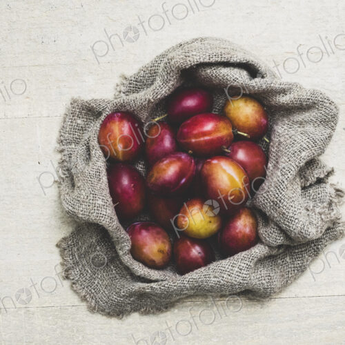 High angle close up of fresh damsons on grey cloth.