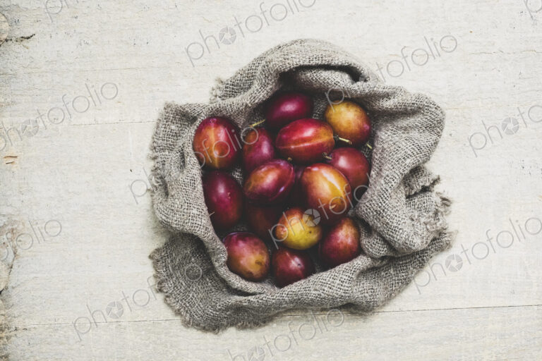 High angle close up of fresh damsons on grey cloth.