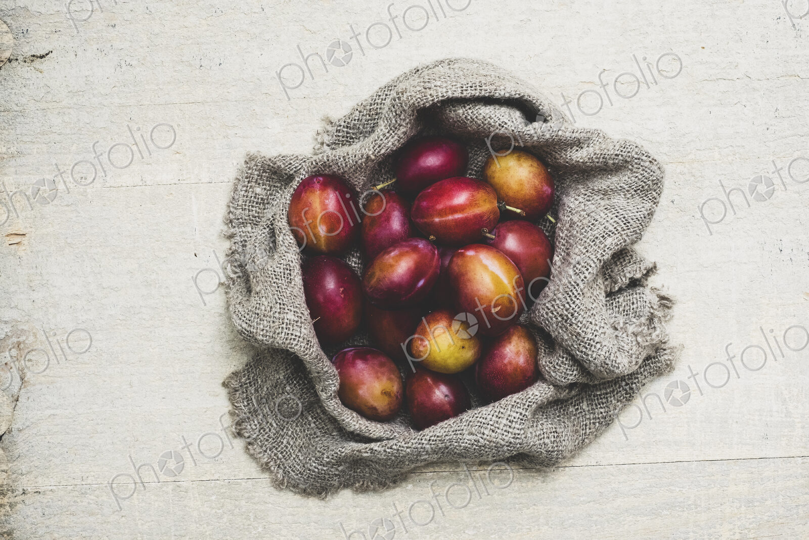 High angle close up of fresh damsons on grey cloth.