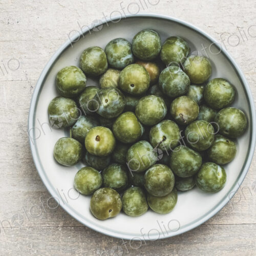 High angle close up of fresh greengages in white bowl. High angle close up of fresh greengages in white bowl.