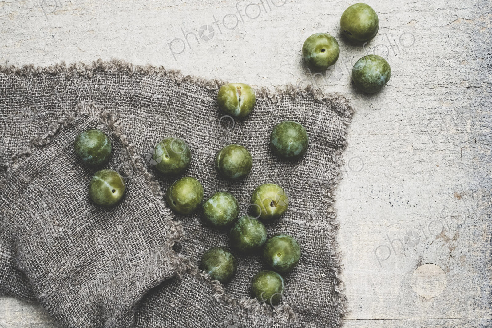 High angle close up of fresh greengages on grey cloth.