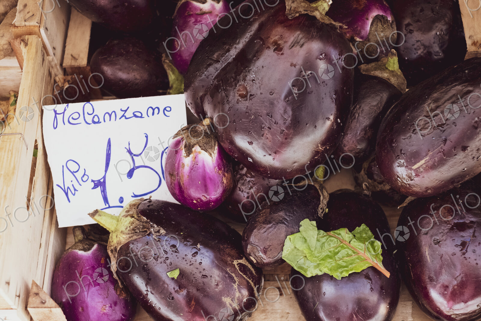 High angle close up of fresh purple aubergines at an Italian market stall.