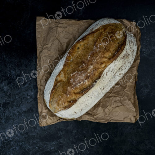 High angle close up of freshly baked loaf of bread on black background.