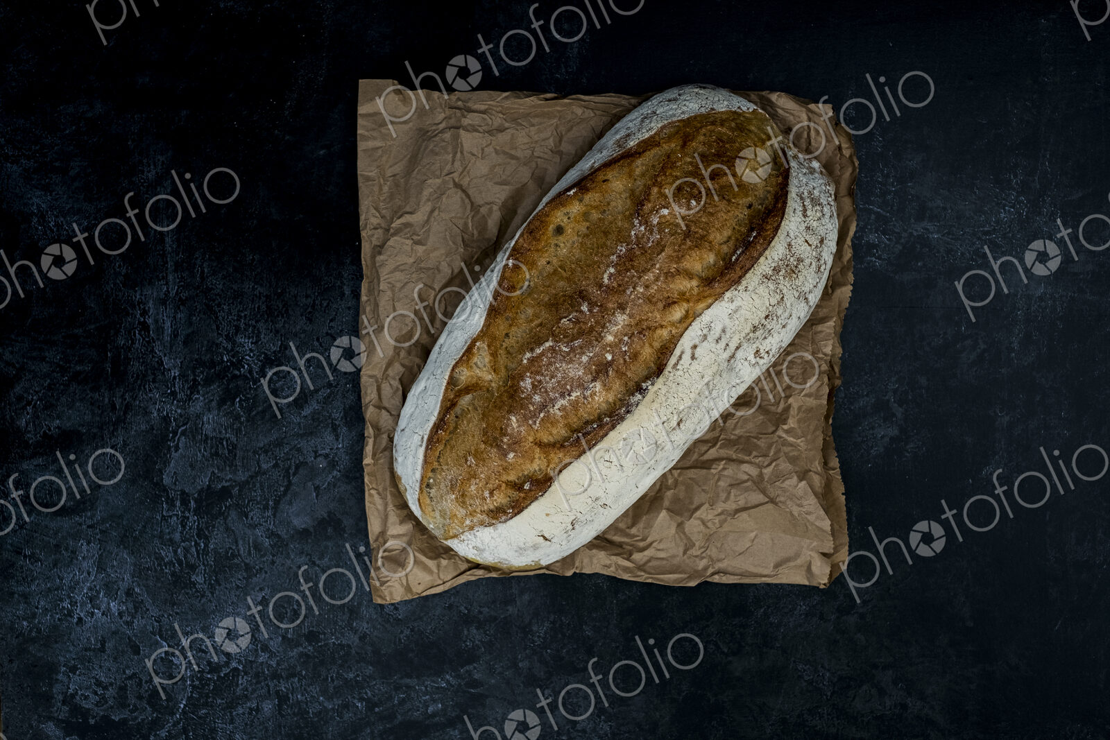 High angle close up of freshly baked loaf of bread on black background.