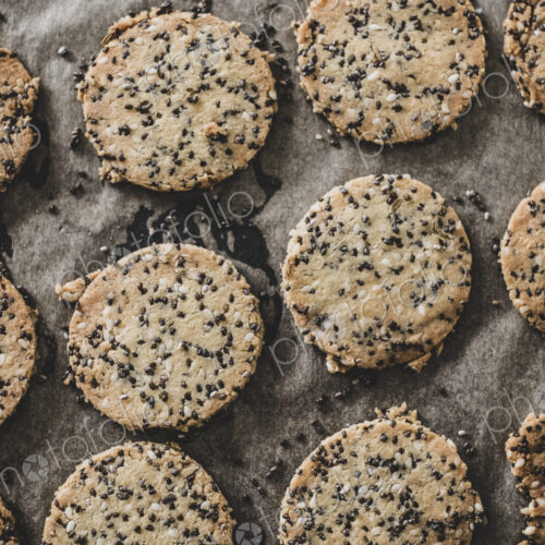 High angle close up of freshly baked seeded crackers on a baking tray.