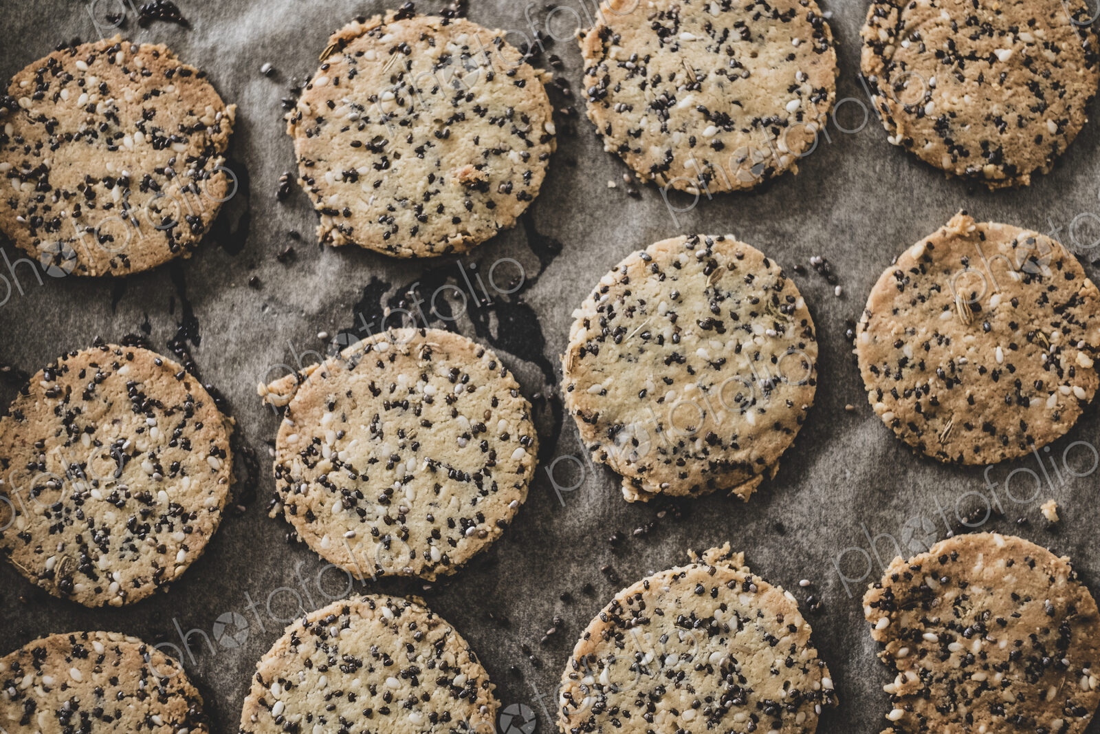 High angle close up of freshly baked seeded crackers on a baking tray.