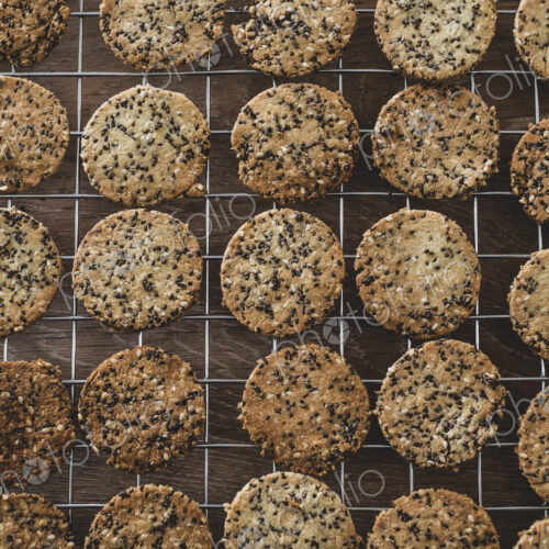 High angle close up of freshly baked seeded crackers on a baking tray.