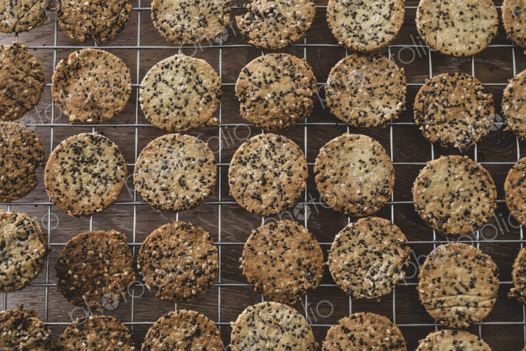 High angle close up of freshly baked seeded crackers on a baking tray.