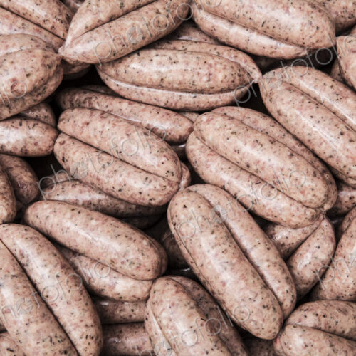 High angle close up of freshly made pork sausages at a butcher shop.