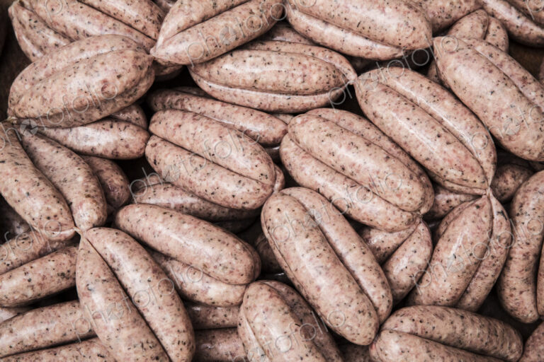 High angle close up of freshly made pork sausages at a butcher shop.