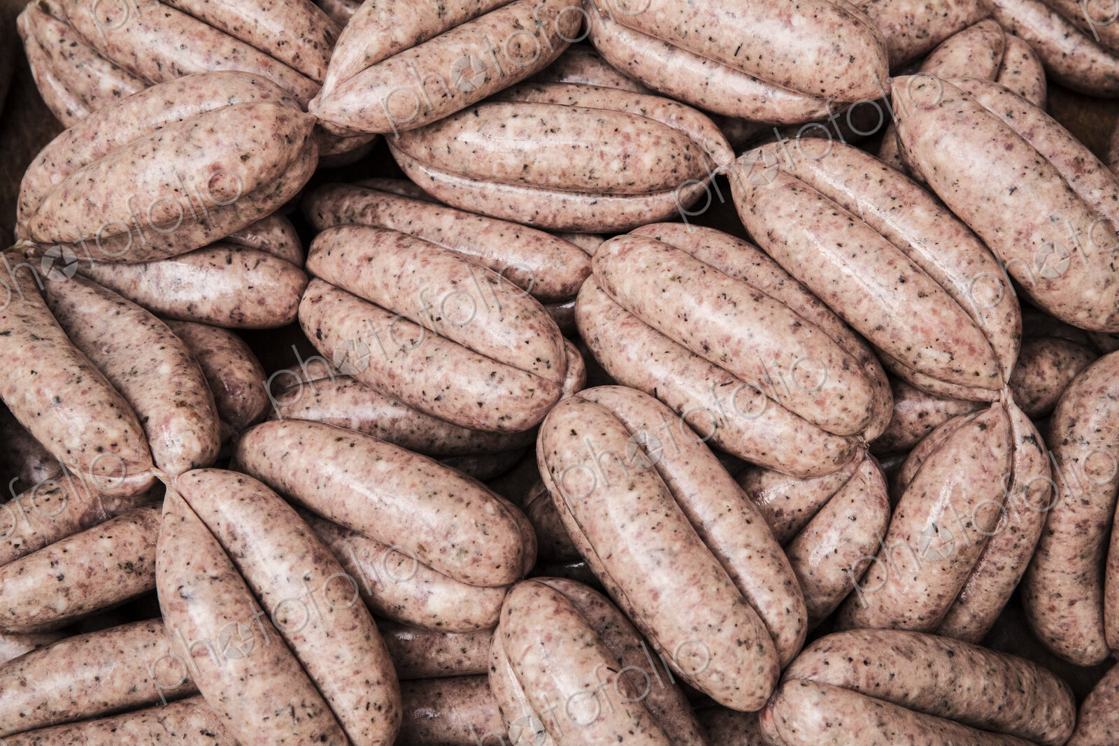 High angle close up of freshly made pork sausages at a butcher shop.