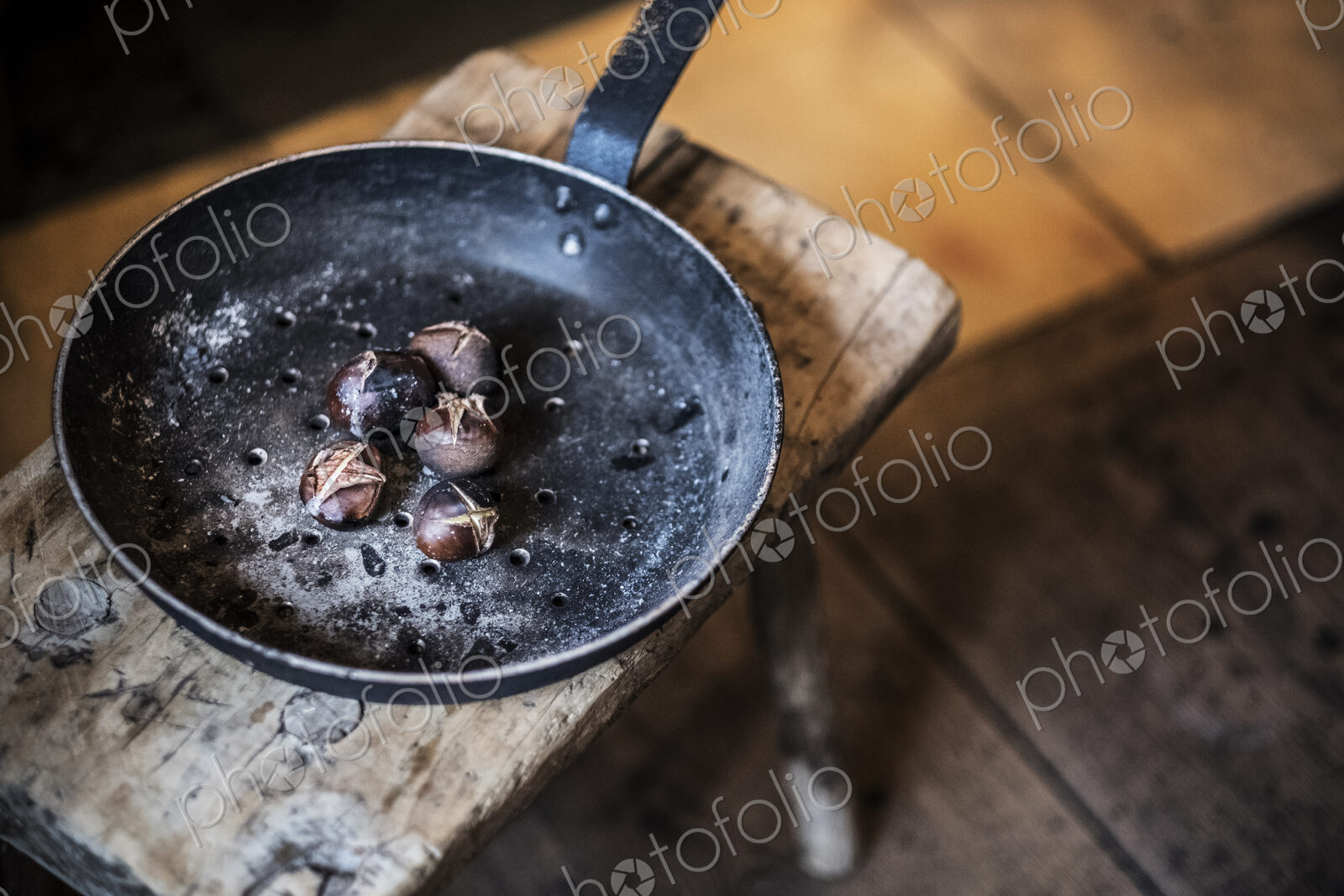 High angle close up of frying pan with freshly roasted chestnuts on rustic wooden table.