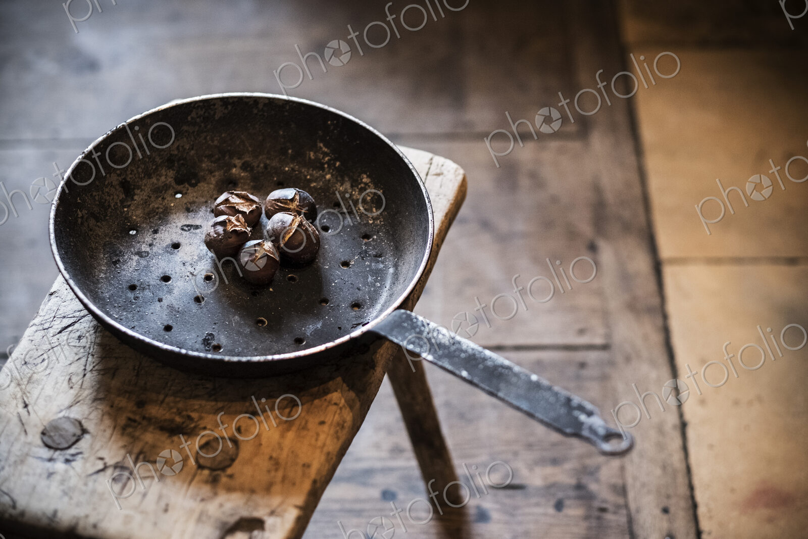 High angle close up of frying pan with freshly roasted chestnuts on rustic wooden table.