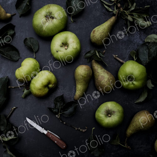 High angle close up of green pears and Bramley apples on black background. High angle close up of green pears and Bramley apples on black background.