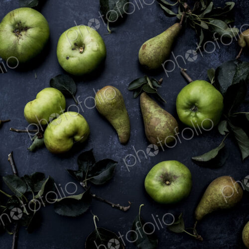 High angle close up of green pears and Bramley apples on black background. High angle close up of green pears and Bramley apples on black background.