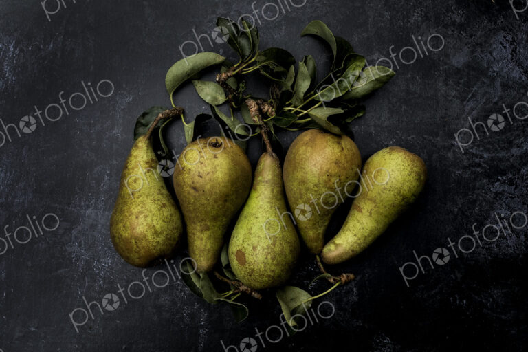 High angle close up of green pears on black background.