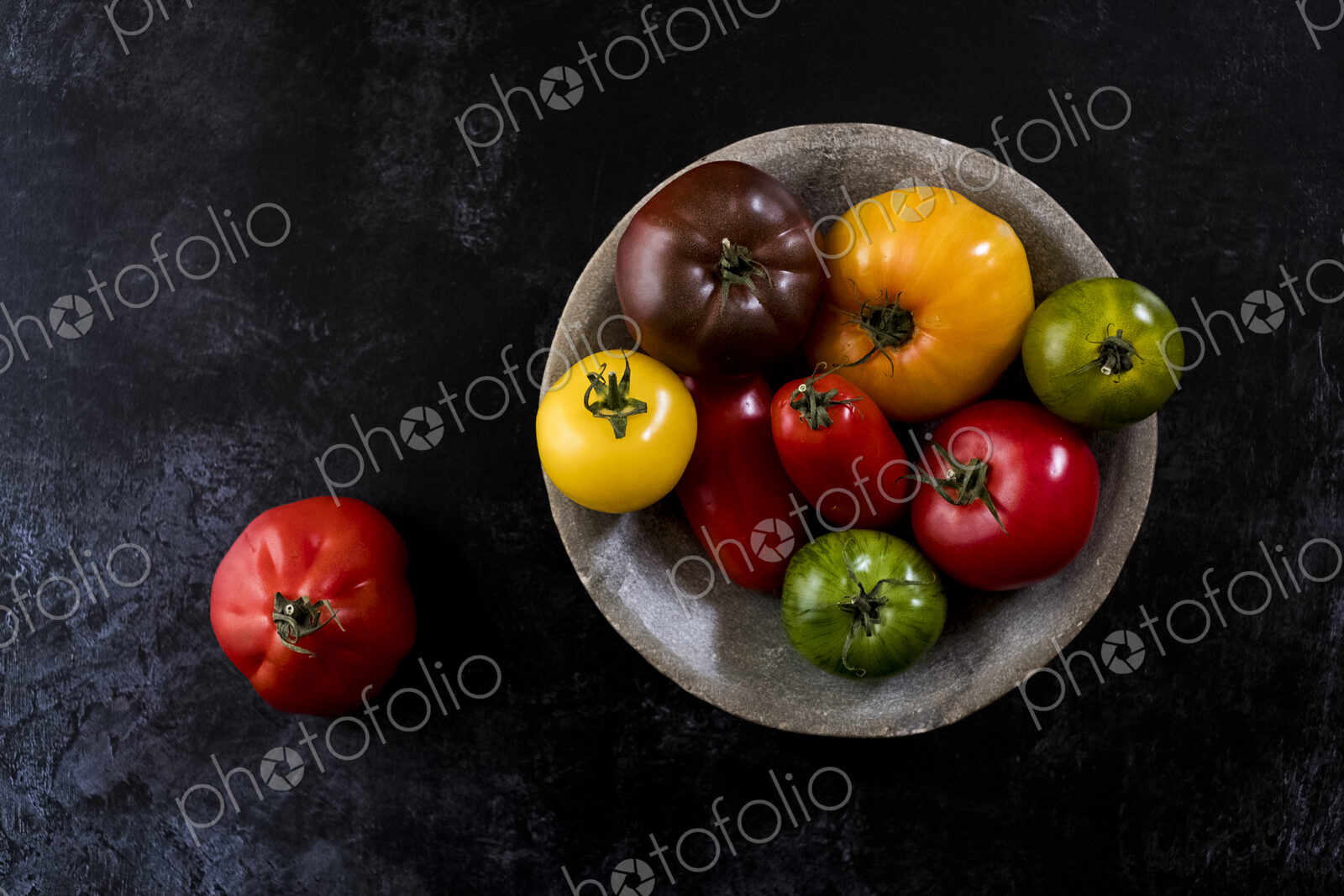 High angle close up of grey plate with selection of tomatoes in various shapes and…