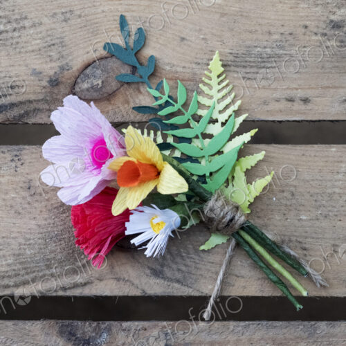 High angle close up of handcrafted boutonniere on a wooden table.