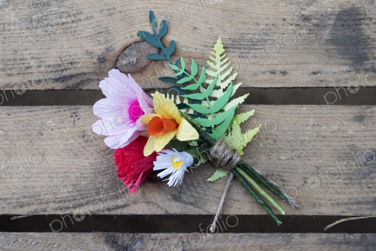 High angle close up of handcrafted boutonniere on a wooden table.