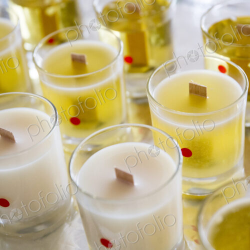 High angle close up of handmade white and yellow jar candles with wooden wick. High angle close up of handmade white and yellow jar candles with wooden wick.