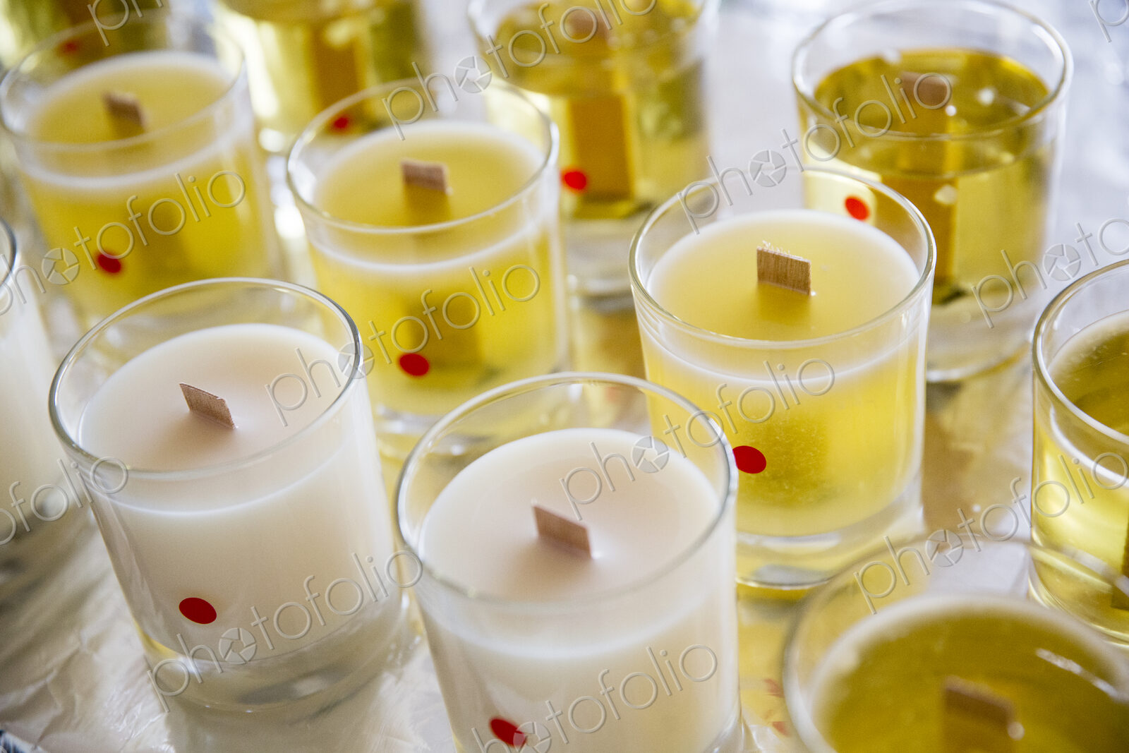 High angle close up of handmade white and yellow jar candles with wooden wick.