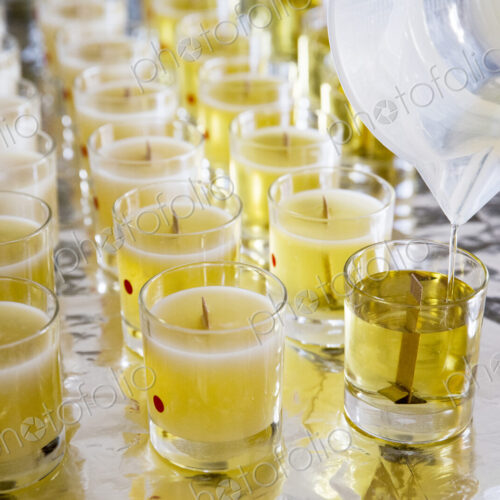 High angle close up of handmade white and yellow jar candles with wooden wick.