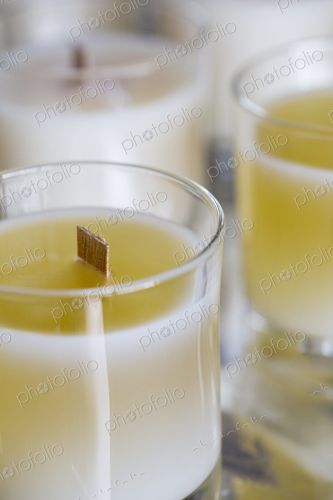 High angle close up of handmade white and yellow jar candles with wooden wick.