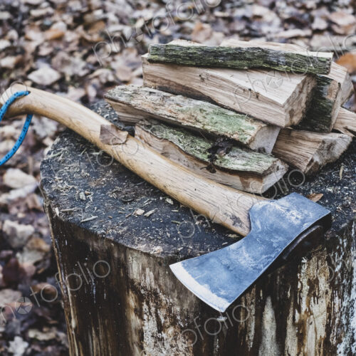 High angle close up of hatchet and wooden logs on chopping block. High angle close up of hatchet and wooden logs on chopping block.