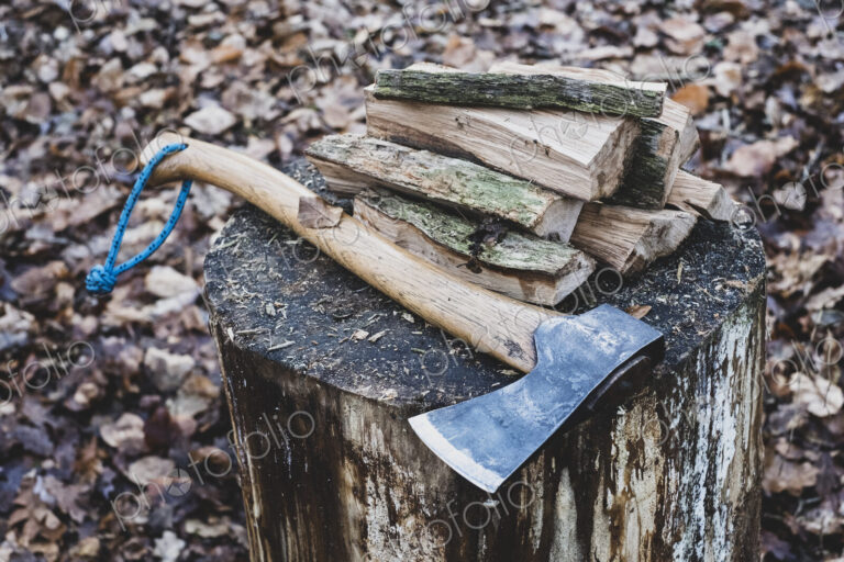 High angle close up of hatchet and wooden logs on chopping block.