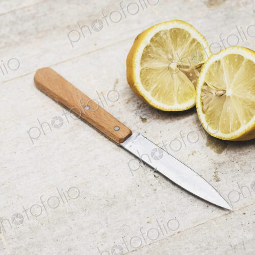 High angle close up of kitchen knife and fresh lemon sliced in half. High angle close up of kitchen knife and fresh lemon sliced in half.