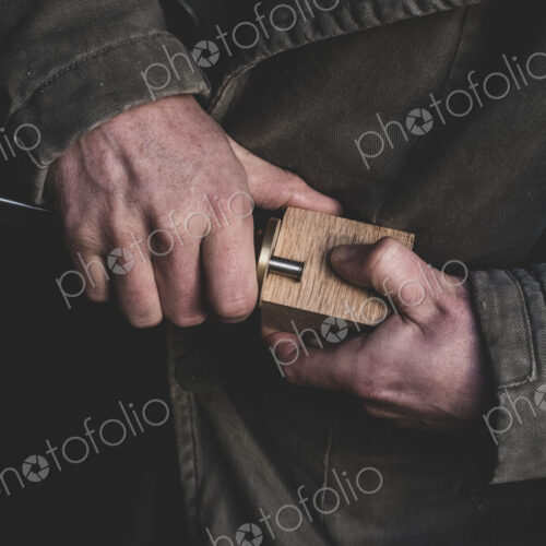 High angle close up of man fitting metal part onto wooden block. High angle close up of man fitting metal part onto wooden block.