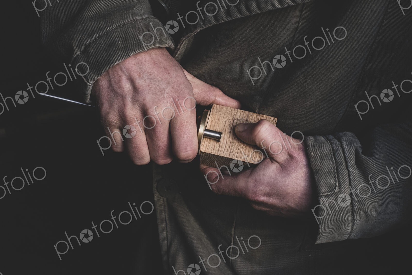 High angle close up of man fitting metal part onto wooden block.