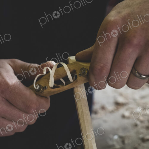 High angle close up of man using plane on piece of wood. High angle close up of man using plane on piece of wood.
