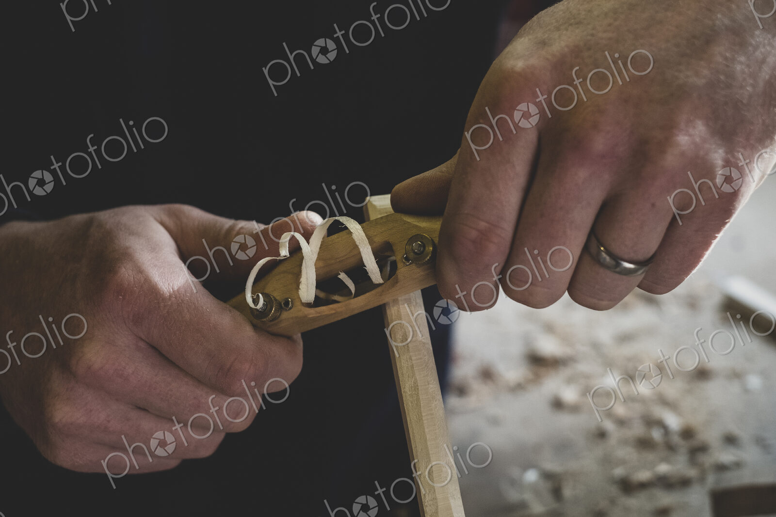 High angle close up of man using plane on piece of wood.