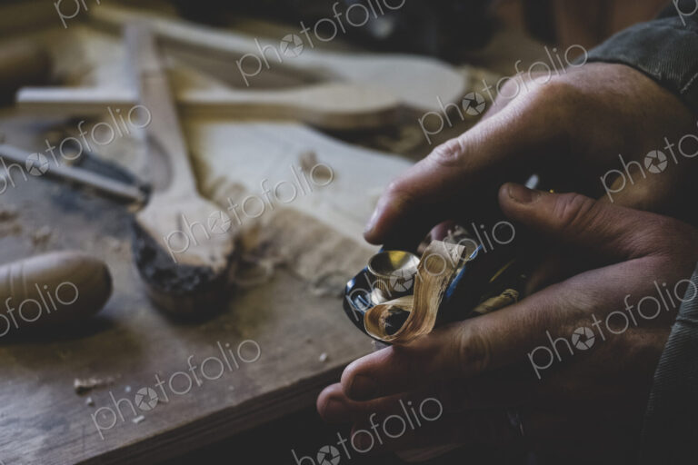 High angle close up of man using plane on piece of wood.