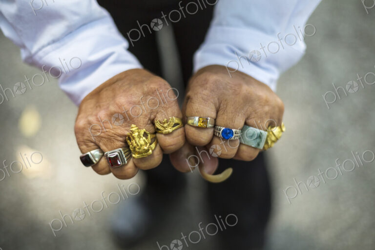 High angle close up of man wearing large ring on each finger.
