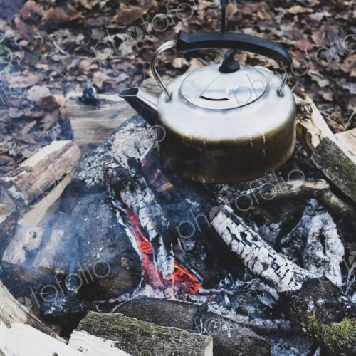 High angle close up of metal kettle hanging over a campfire. High angle close up of metal kettle hanging over a campfire.