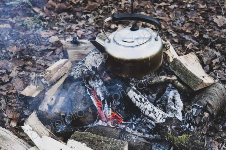 High angle close up of metal kettle hanging over a campfire.
